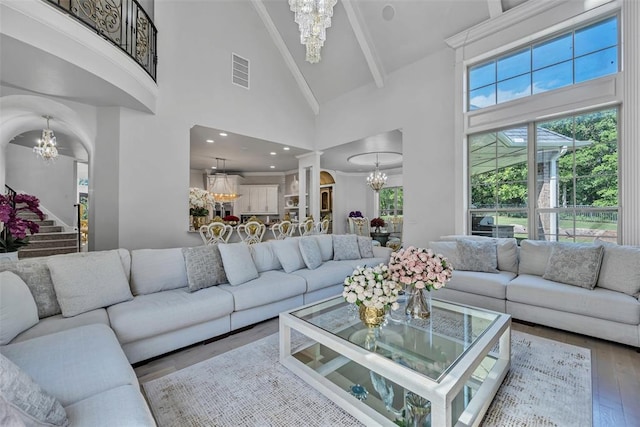 living room with beamed ceiling, a notable chandelier, wood-type flooring, and high vaulted ceiling