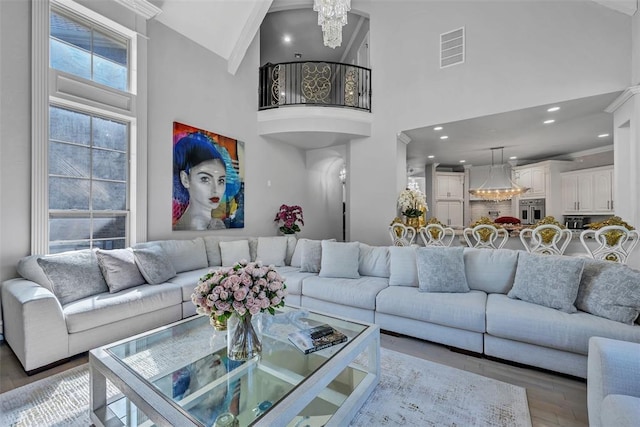 living room featuring wood-type flooring, high vaulted ceiling, and a notable chandelier