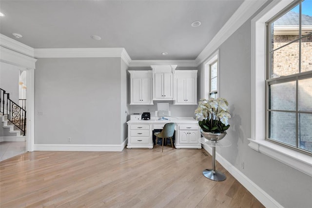 home office with built in desk, plenty of natural light, and ornamental molding