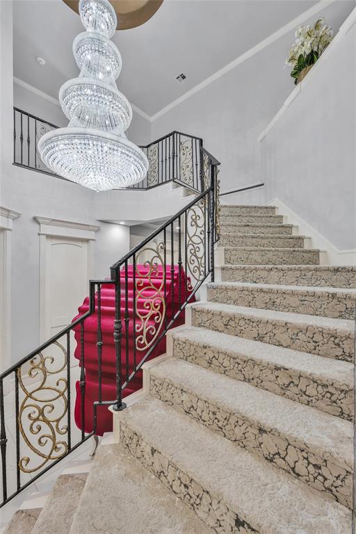 stairway featuring a notable chandelier, crown molding, and a high ceiling