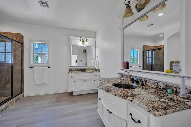 bathroom with hardwood / wood-style flooring, vanity, and an enclosed shower