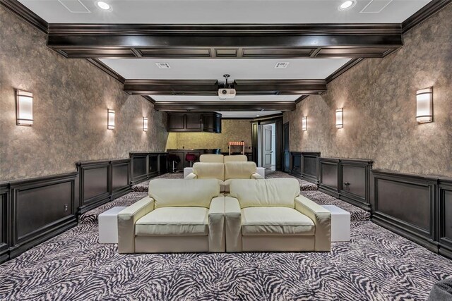 carpeted home theater room featuring beam ceiling and ornamental molding