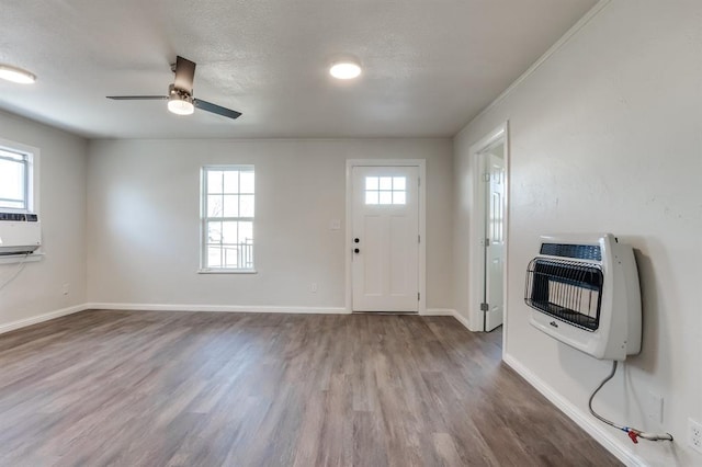 foyer entrance featuring hardwood / wood-style floors, ceiling fan, cooling unit, heating unit, and a textured ceiling