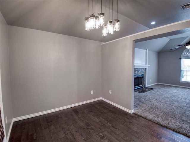 interior space with a tiled fireplace, dark hardwood / wood-style floors, vaulted ceiling, and ceiling fan with notable chandelier