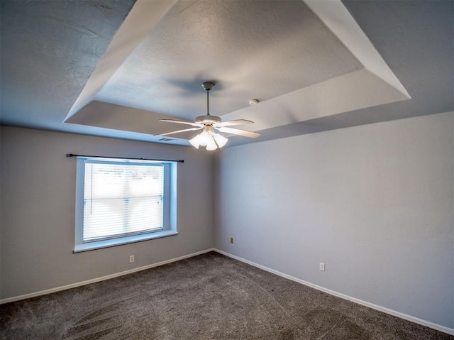 carpeted spare room featuring ceiling fan and a tray ceiling