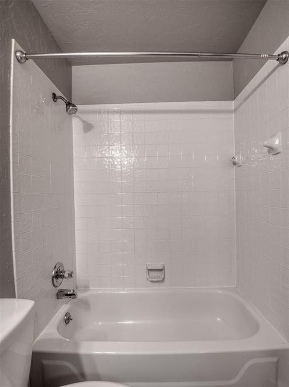 bathroom with tiled shower / bath combo and toilet