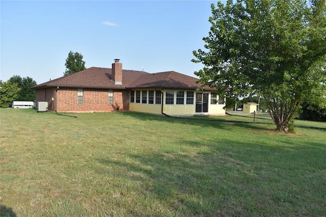 back of property featuring a sunroom, a yard, and central AC unit