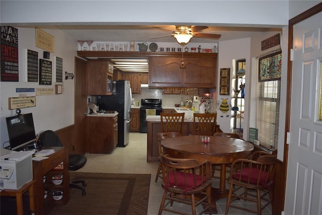 dining area featuring sink, ceiling fan, and wood walls