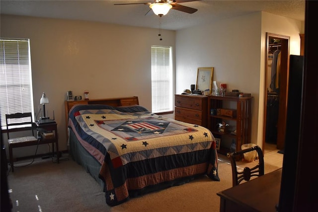 carpeted bedroom with a walk in closet, a closet, and ceiling fan