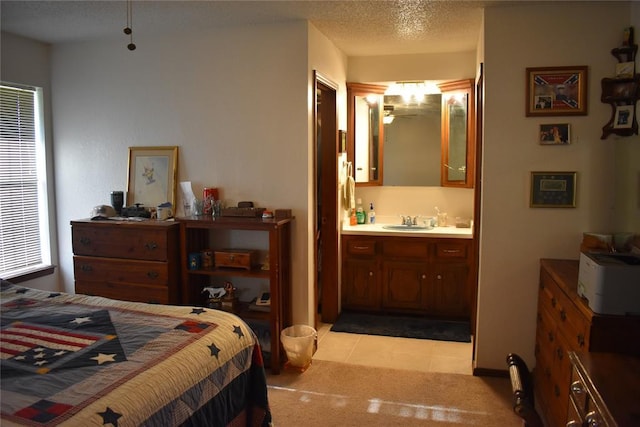 carpeted bedroom featuring a textured ceiling, sink, and ensuite bath