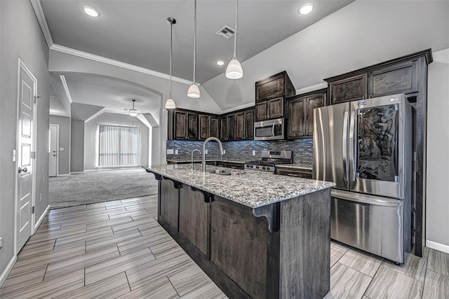 kitchen with a kitchen bar, stainless steel appliances, dark brown cabinets, light stone countertops, and pendant lighting