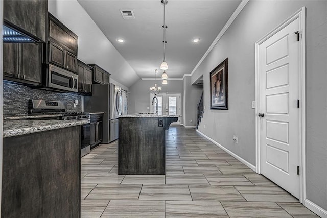 kitchen featuring an island with sink, a breakfast bar area, stainless steel appliances, decorative light fixtures, and light stone countertops