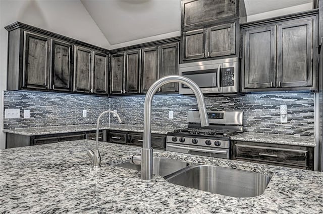 kitchen with stainless steel appliances, lofted ceiling, tasteful backsplash, and light stone countertops