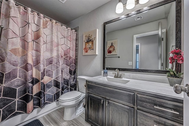 bathroom with toilet, vanity, and hardwood / wood-style floors