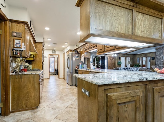 kitchen with sink, light stone counters, light tile patterned floors, stainless steel fridge, and kitchen peninsula