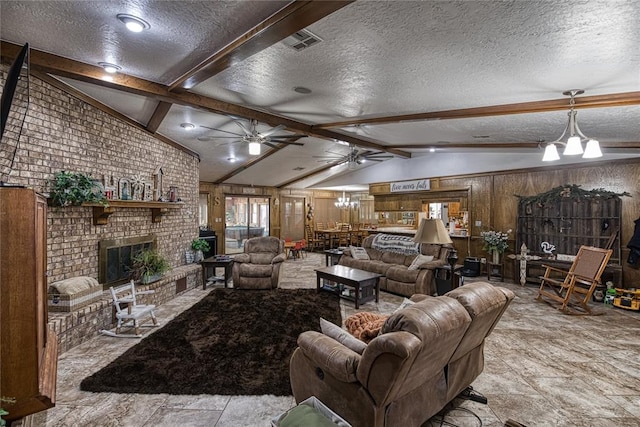 living room with ceiling fan with notable chandelier, a fireplace, wood walls, lofted ceiling with beams, and a textured ceiling