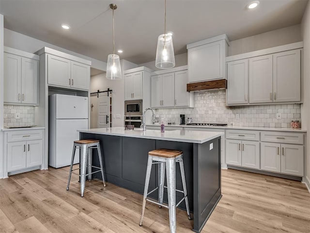 kitchen with a breakfast bar, backsplash, sink, a barn door, and stainless steel appliances