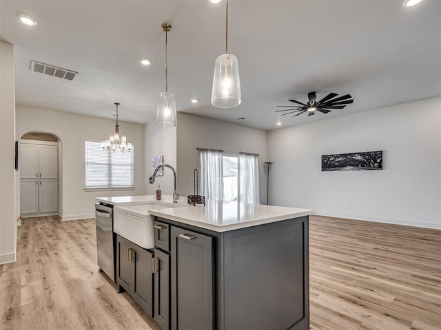 kitchen featuring sink, stainless steel dishwasher, an island with sink, decorative light fixtures, and ceiling fan with notable chandelier