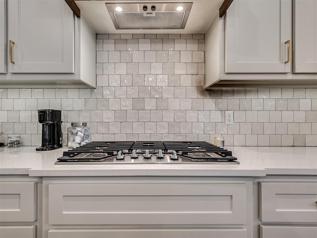 kitchen featuring decorative backsplash, white cabinets, and stainless steel gas stovetop