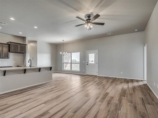 interior space featuring ceiling fan with notable chandelier, light wood-type flooring, and sink