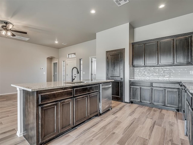 kitchen with decorative backsplash, ceiling fan, sink, dishwasher, and an island with sink