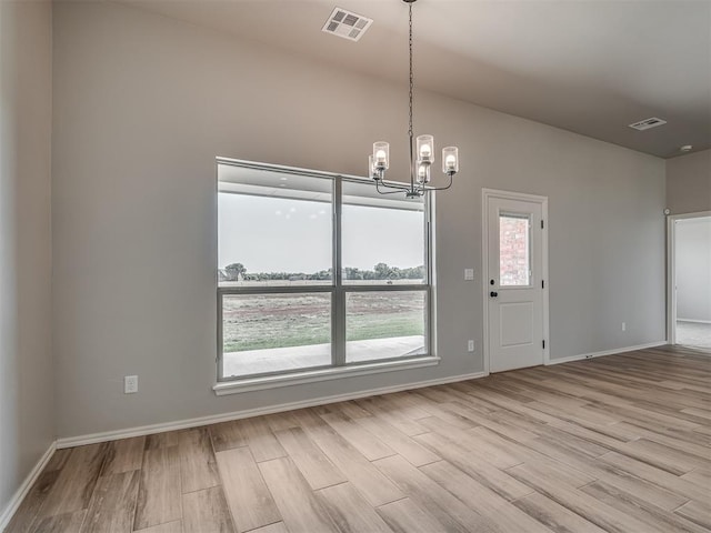 unfurnished dining area featuring light hardwood / wood-style flooring and an inviting chandelier