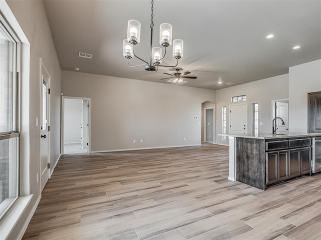 kitchen with dark brown cabinetry, sink, hanging light fixtures, and ceiling fan with notable chandelier