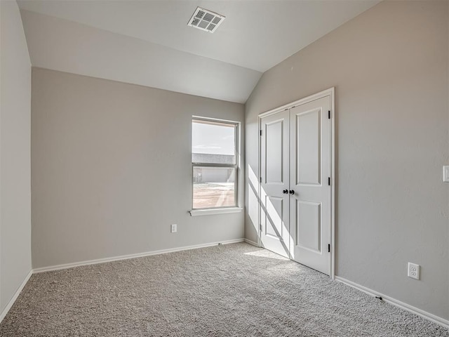 unfurnished bedroom featuring carpet, lofted ceiling, and a closet