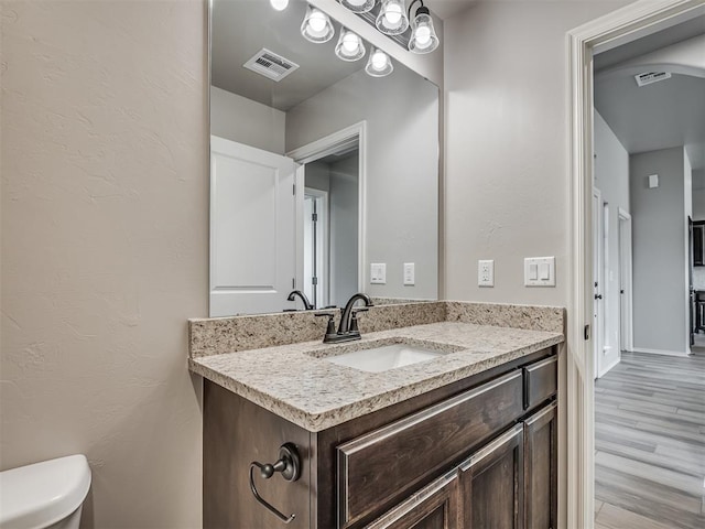 bathroom with hardwood / wood-style floors, vanity, and toilet