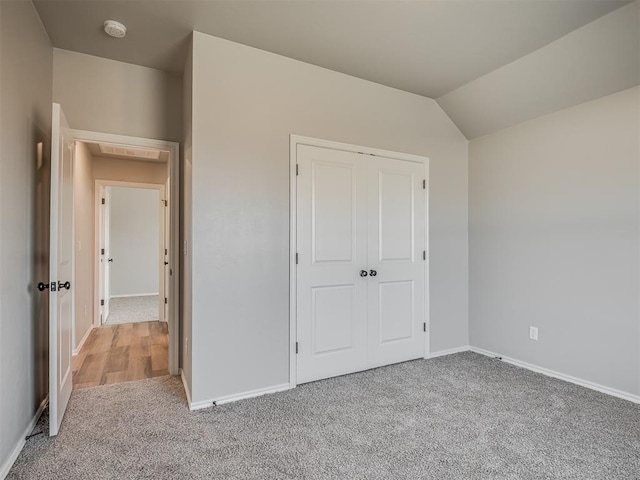 unfurnished bedroom with carpet flooring, a closet, and lofted ceiling