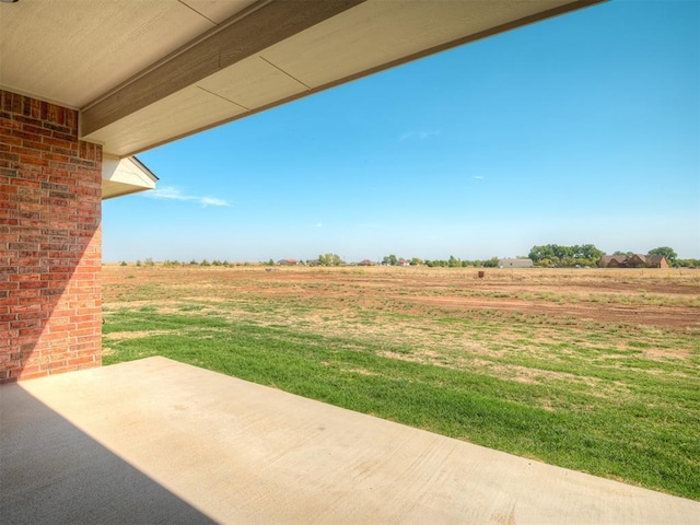 view of yard with a rural view and a patio