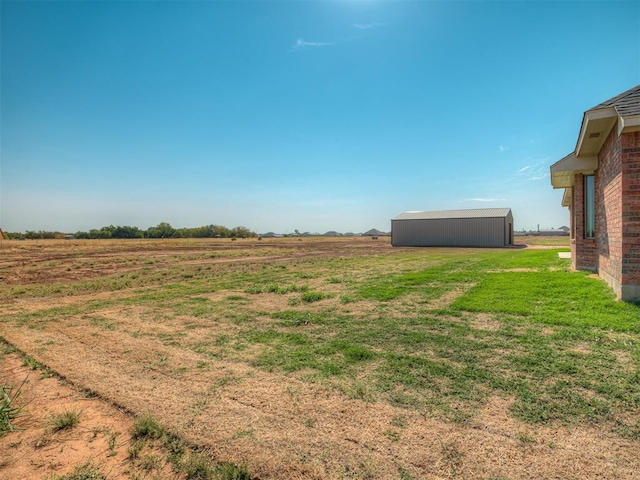 view of yard with a rural view and an outdoor structure