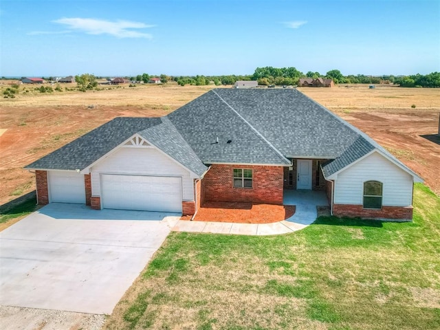 view of front of house featuring a garage, a front yard, and a rural view