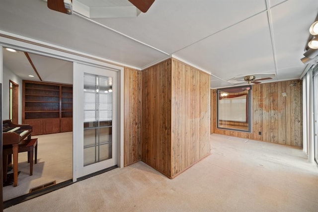 carpeted empty room with wood walls and ceiling fan