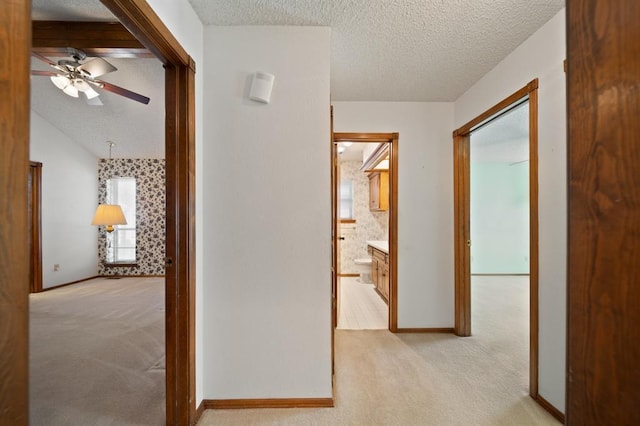 corridor featuring a textured ceiling and light carpet