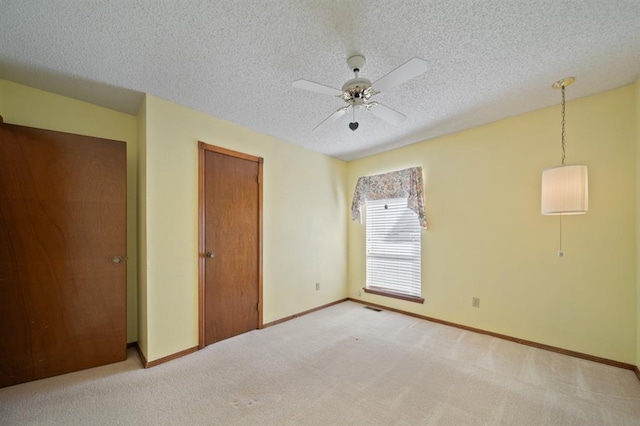 unfurnished bedroom featuring a closet, a textured ceiling, ceiling fan, and light carpet