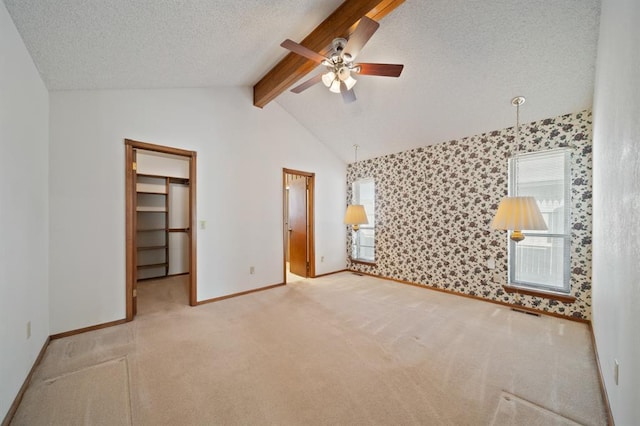 unfurnished bedroom featuring a closet, ceiling fan, a spacious closet, carpet flooring, and a textured ceiling