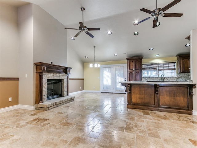 kitchen featuring high vaulted ceiling, a fireplace, a wealth of natural light, and dark brown cabinetry