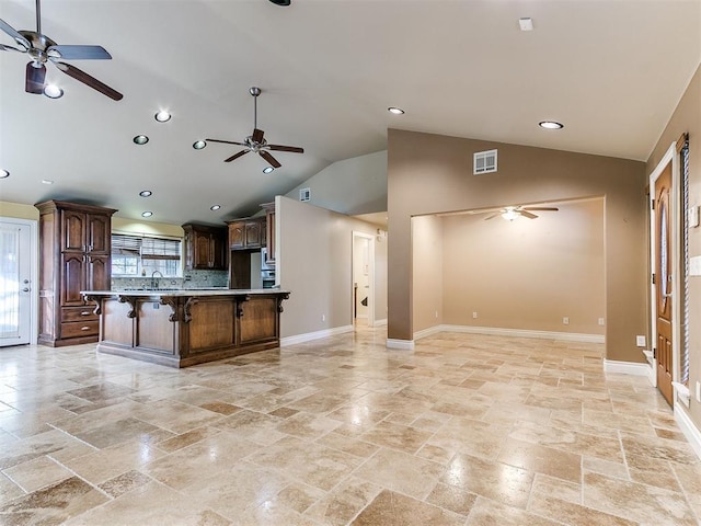 kitchen with vaulted ceiling, a breakfast bar, a kitchen island, sink, and backsplash