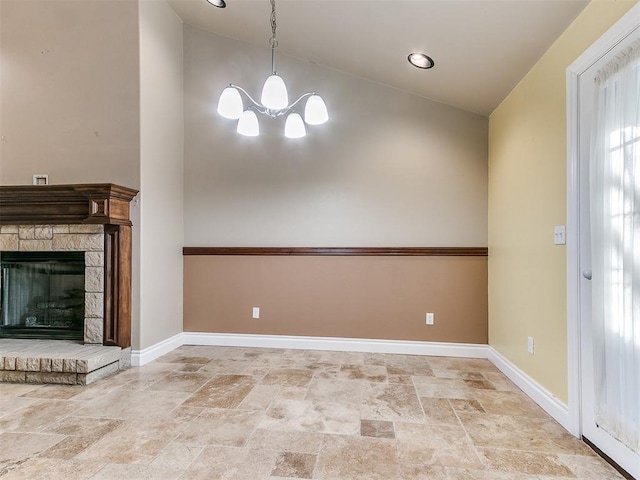 unfurnished dining area with lofted ceiling, a chandelier, plenty of natural light, and a stone fireplace