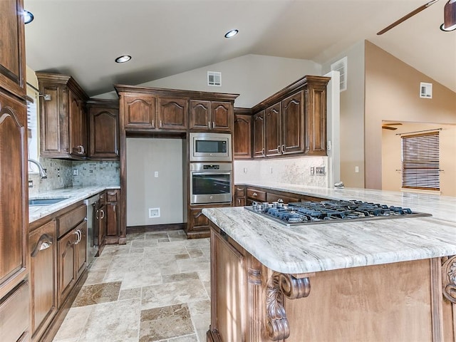 kitchen with stainless steel appliances, sink, vaulted ceiling, dark brown cabinetry, and a kitchen island