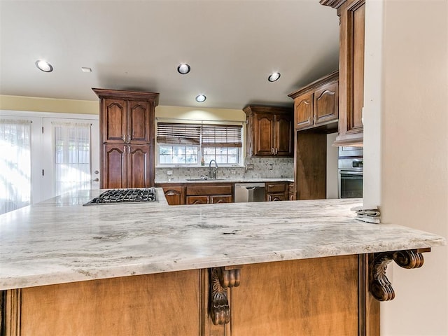 kitchen featuring appliances with stainless steel finishes, sink, backsplash, and kitchen peninsula