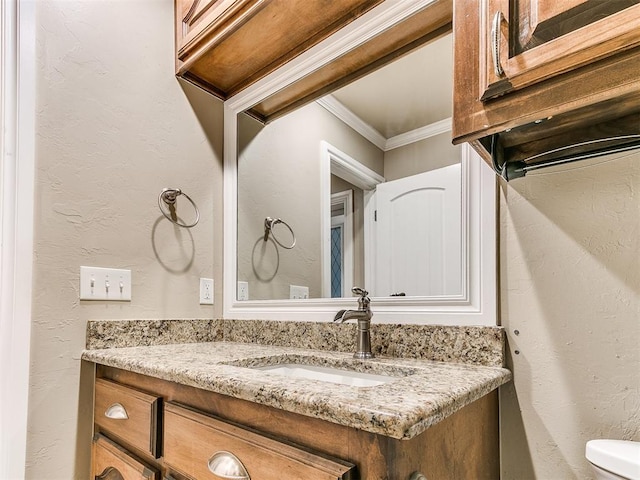 bathroom with toilet, vanity, and crown molding