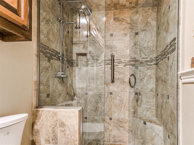 bathroom featuring a shower with shower door and toilet