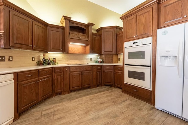 kitchen with backsplash, white appliances, and light hardwood / wood-style flooring