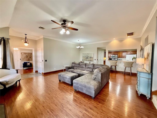 living room with vaulted ceiling, wood-type flooring, ceiling fan with notable chandelier, and ornamental molding