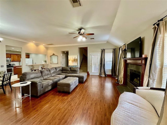 living room featuring wood-type flooring, vaulted ceiling, ceiling fan, and ornamental molding