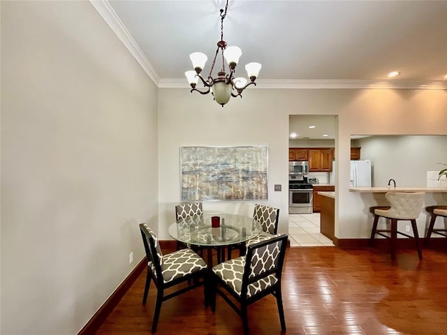 dining area with hardwood / wood-style flooring, an inviting chandelier, and crown molding