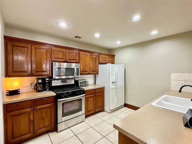 kitchen with decorative backsplash, sink, light tile patterned floors, and stainless steel appliances