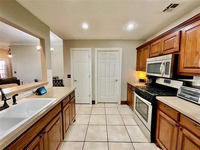 kitchen with sink, light tile patterned floors, stainless steel appliances, and ornamental molding